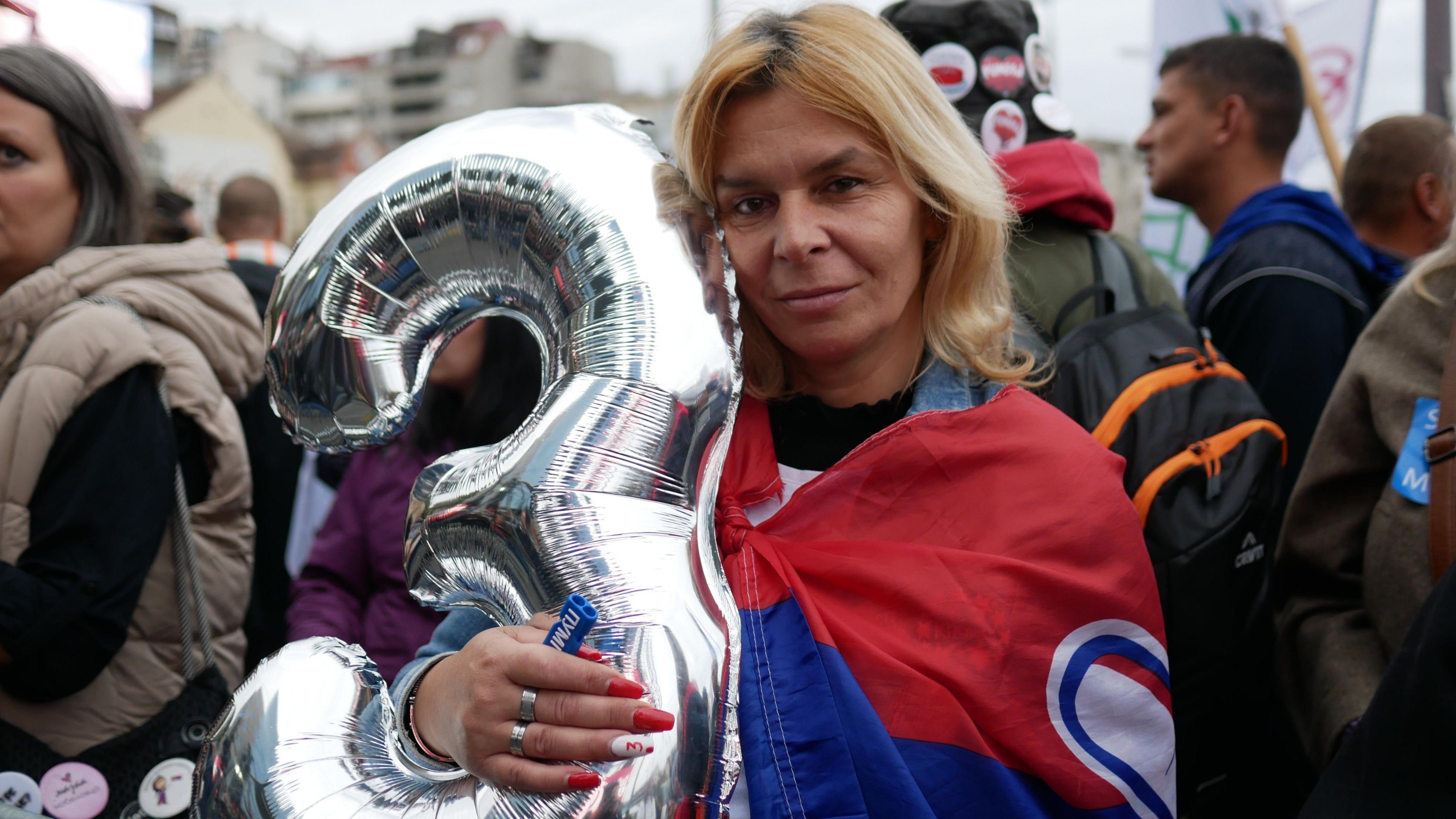 Supporter hugs the Student List flag at a rally in Belgrade
