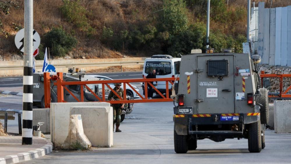 Israeli army vehicle passing near the closed entrance of Hebron in the West Bank
