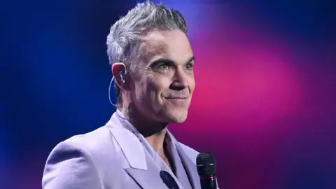 Robbie Williams Reflects on British Self-Devaluation and His Musical Journey