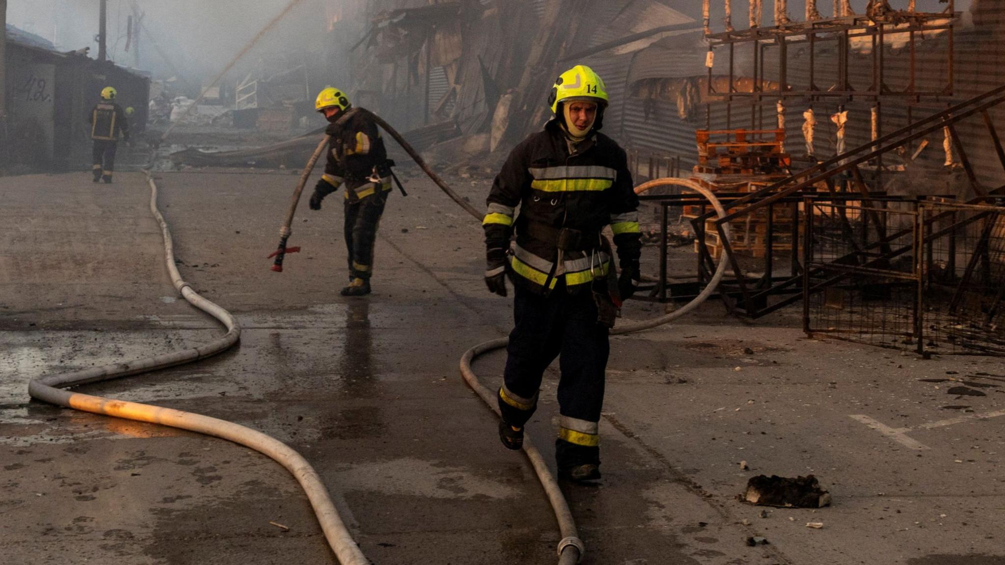 Firefighters try to extinguish the blaze after a warehouse in Kyiv was hit by Russian missile strikes