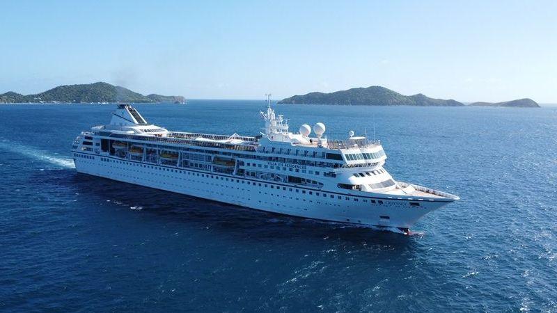 A white cruise ship sails in blue waters