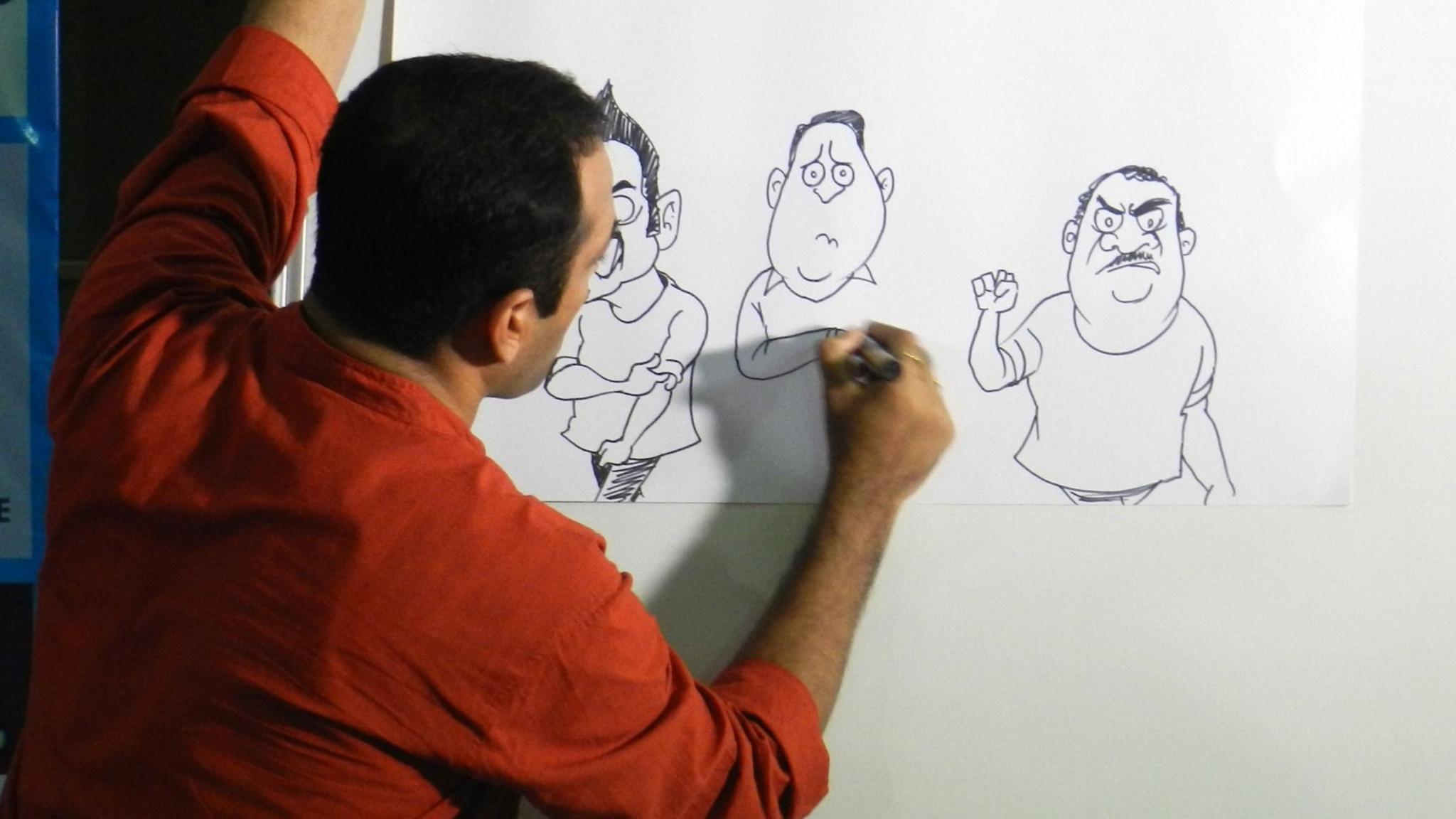 Satish Acharya drawing cartoons for a whiteboard